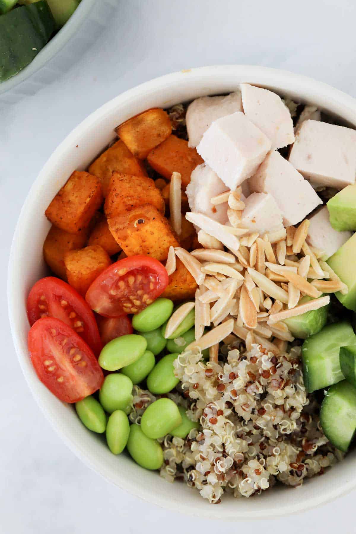 A quinoa chicken bowl with the ingredients placed individually in the bowl.