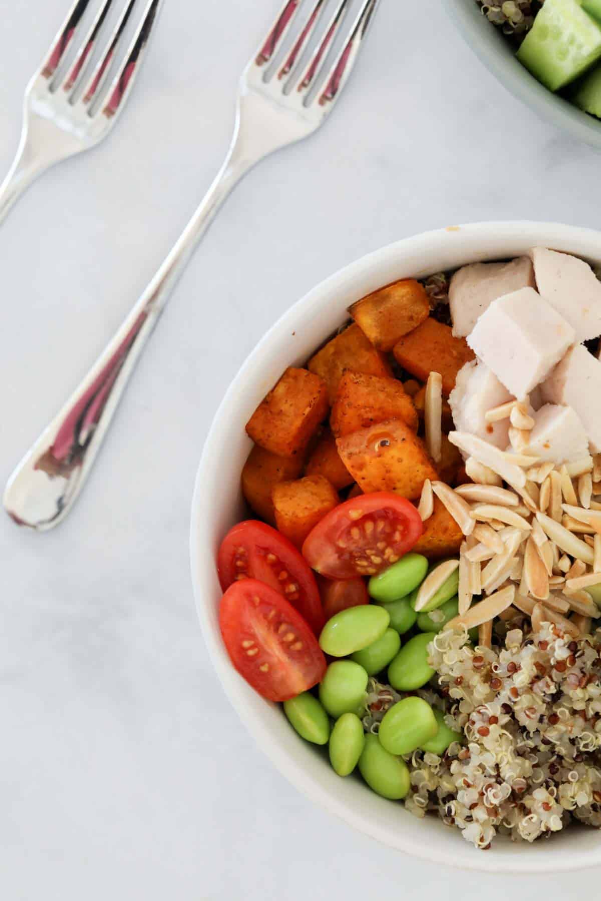 Ingredients for quinoa bowl placed in a bowl before being mixed and tossed in dressing.