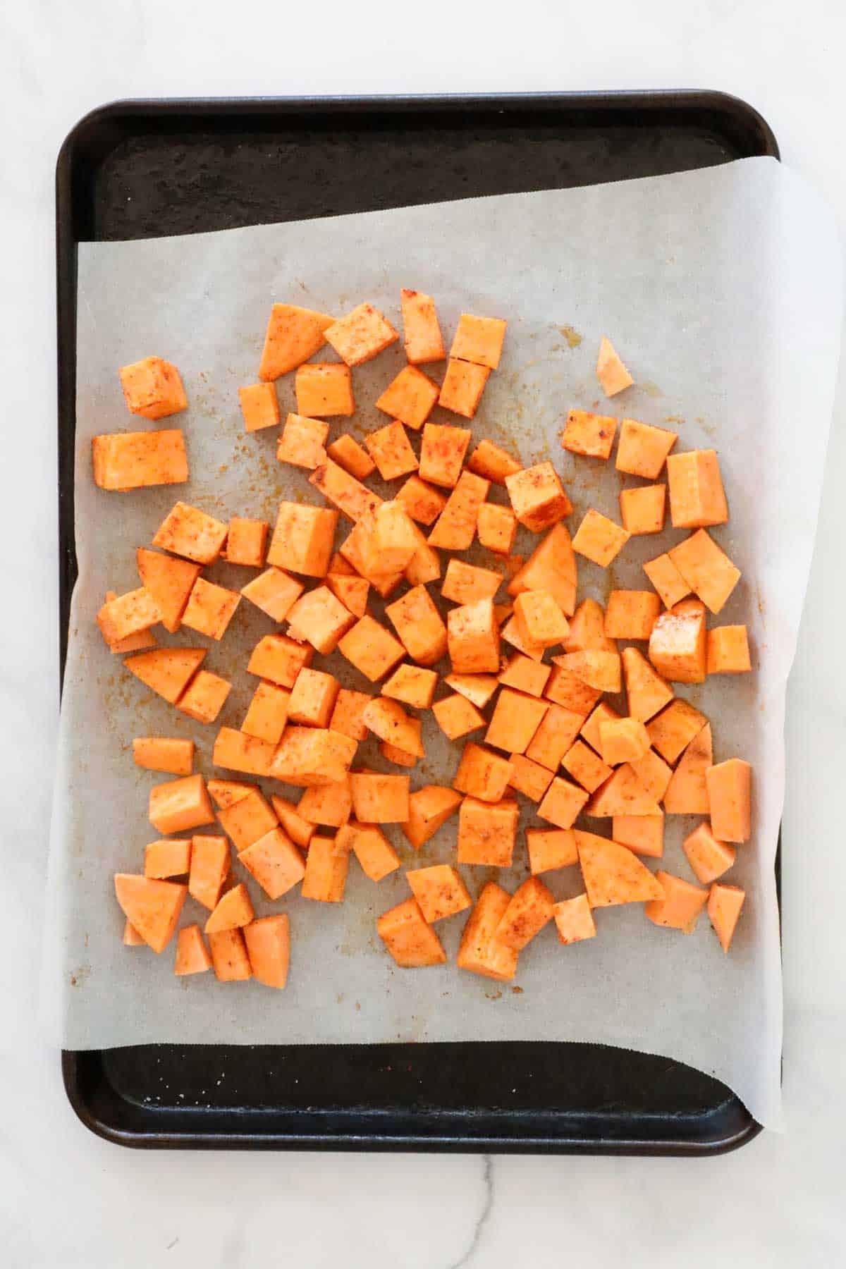 Diced sweet potato on a baking sheet lined with baking paper.