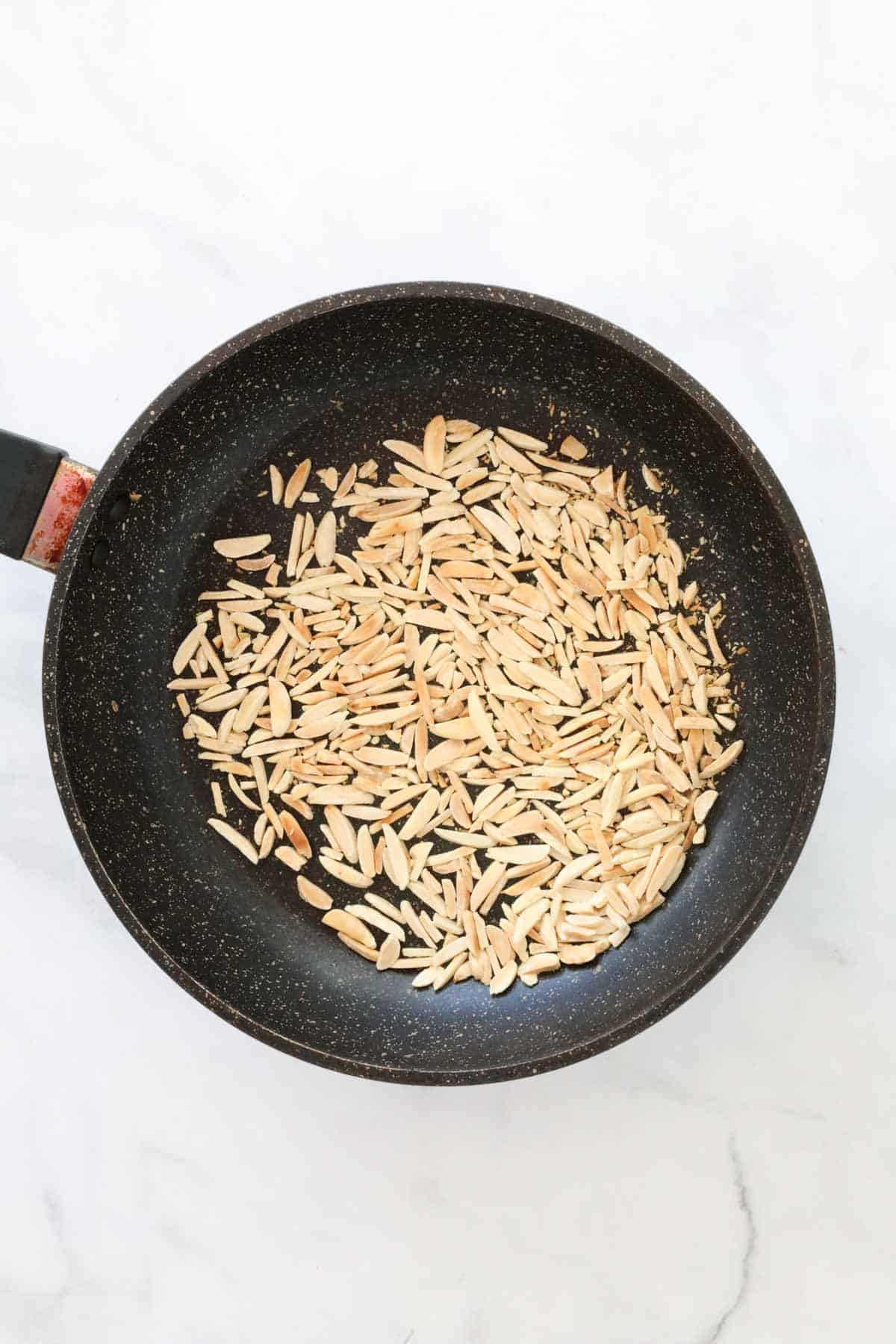 Toasted slivered almonds in a small frying pan.