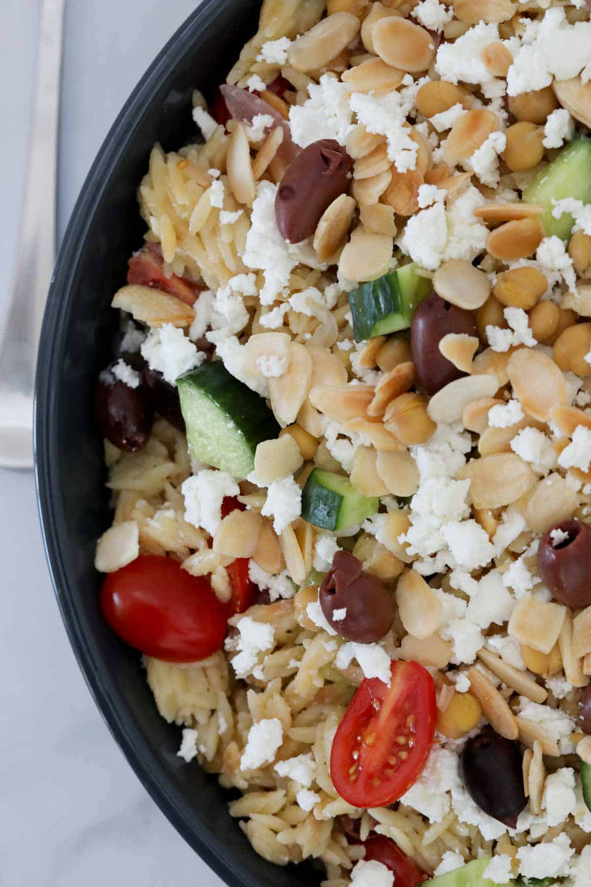 Close up of the finished salad in a serving bowl with toasted flaked almonds and crumbled feta on top.