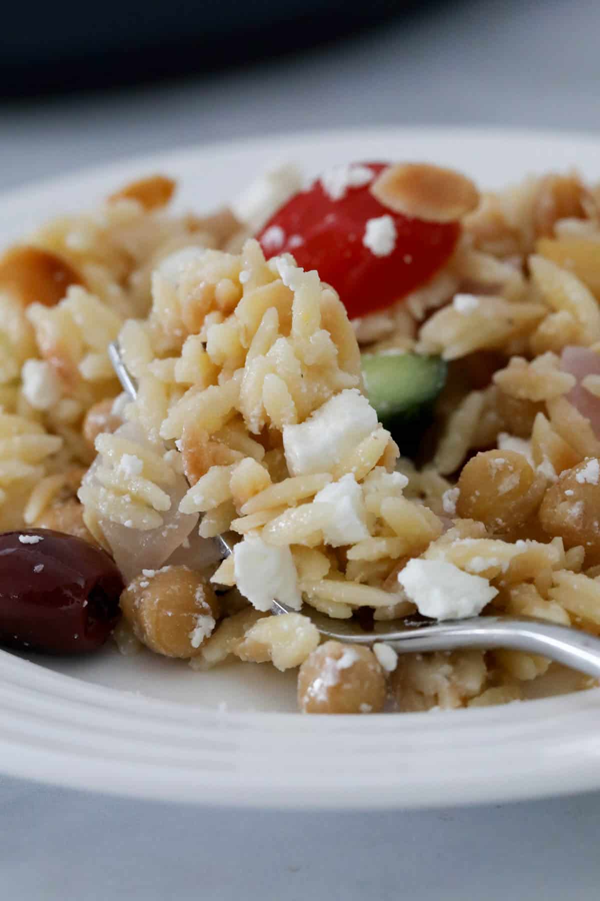 Close up of Greek risoni salad on a white plate.