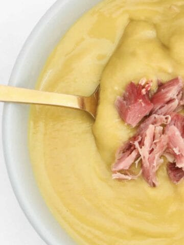 A bowl of creamy pea and ham soup.
