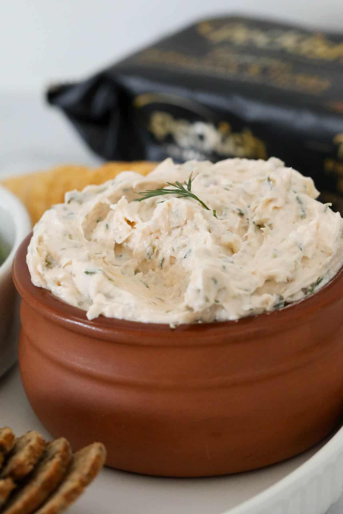 A close up of a terrcotta bowl filled with a creamy salmon dip.