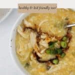 Thick chicken and corn soup in a bowl, with soy sauce and spring onions on top.