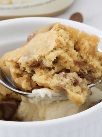 A spoon holding a microwave cookie cooked in a mug.