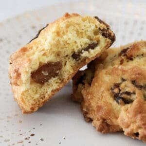 Two rock cakes with grated orange zezt and sultanas on a plate.