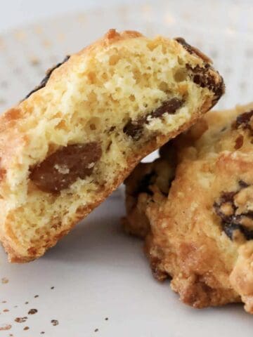 Two rock cakes with grated orange zezt and sultanas on a plate.