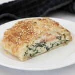 A slice of puff pastry pie filled with salmon, spinach and ricotta.