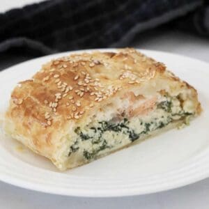 A slice of puff pastry pie filled with salmon, spinach and ricotta.