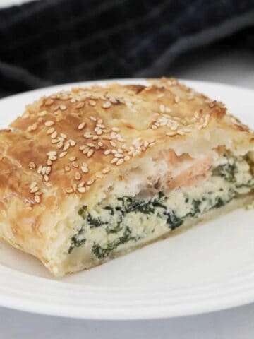 A slice of puff pastry pie filled with salmon, spinach and ricotta.