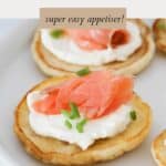 Blinis with a spread of cream cheese, topped with a portion of smoked salmon, and a sprinkle of chopped chives.