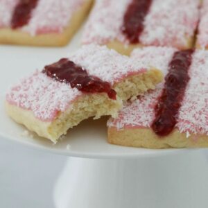 Homemade versions of Arnott's Iced Vovo biscuits on a white cake stand.