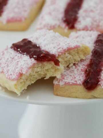 Homemade versions of Arnott's Iced Vovo biscuits on a white cake stand.