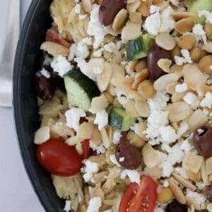 An overhead shot of a bowl of risono salad with Greek flavours including lemon, feta and tomato.