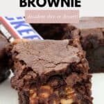 A chocolate brownie filled with gooey melted Snickers bars inside.