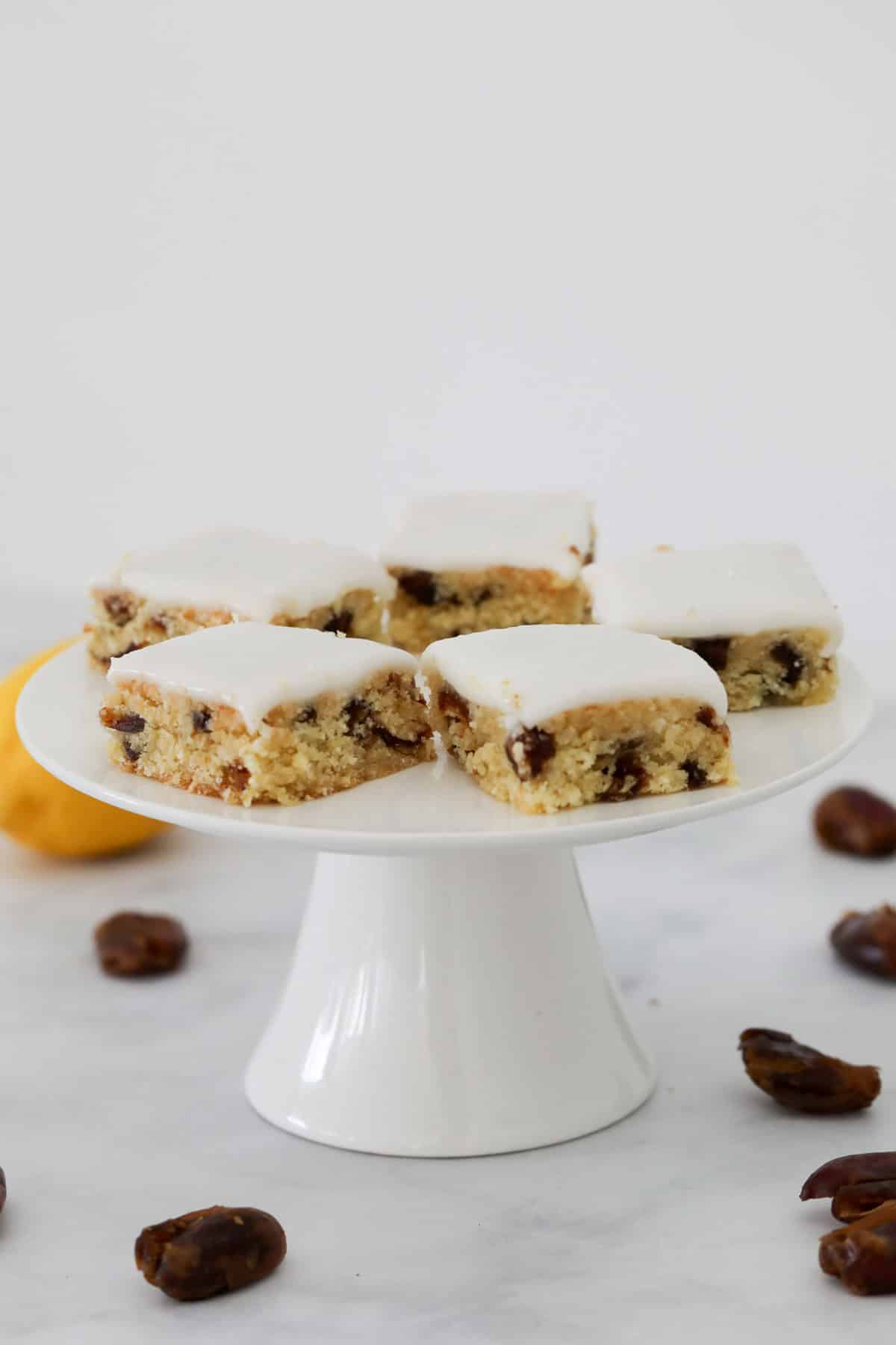 Squares of a slice made with dates and glazed with lemon icing.