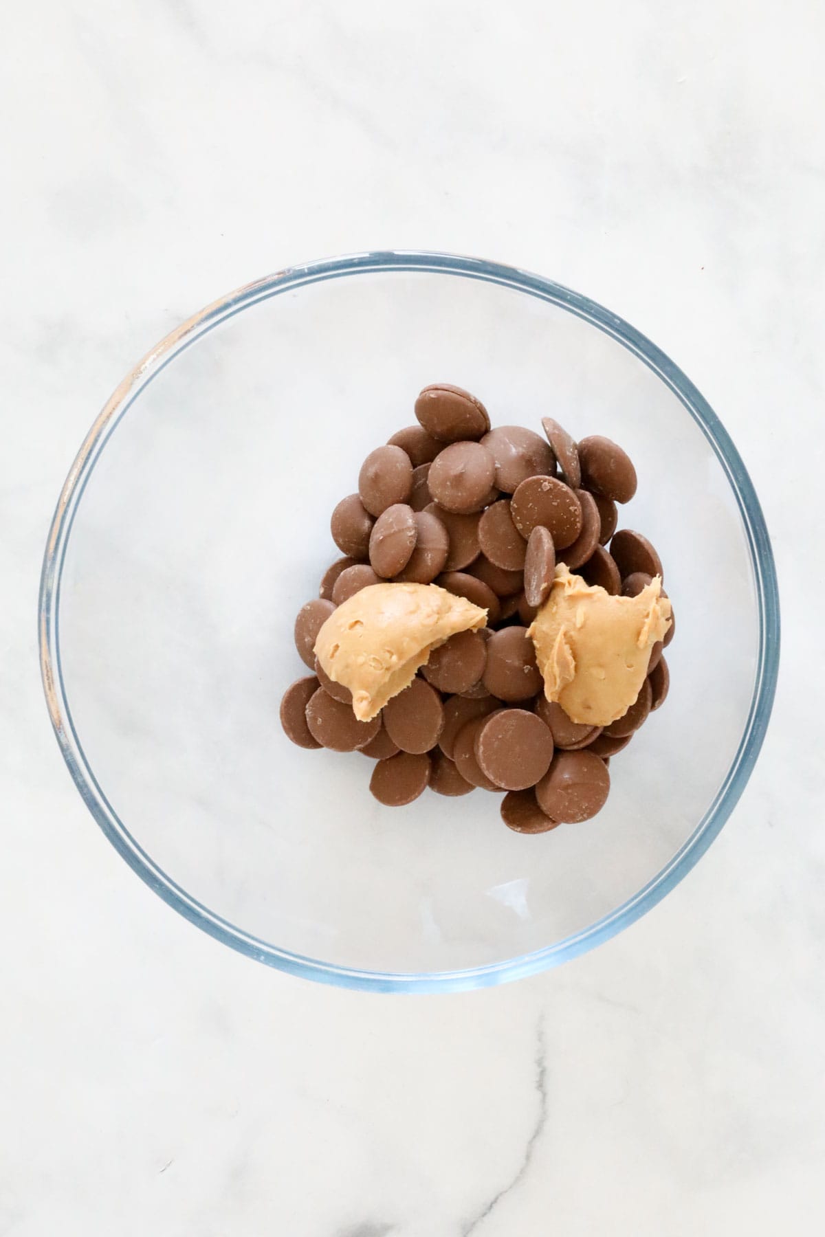 Chocolate melts and peanut butter in a glass microwave safe bowl.