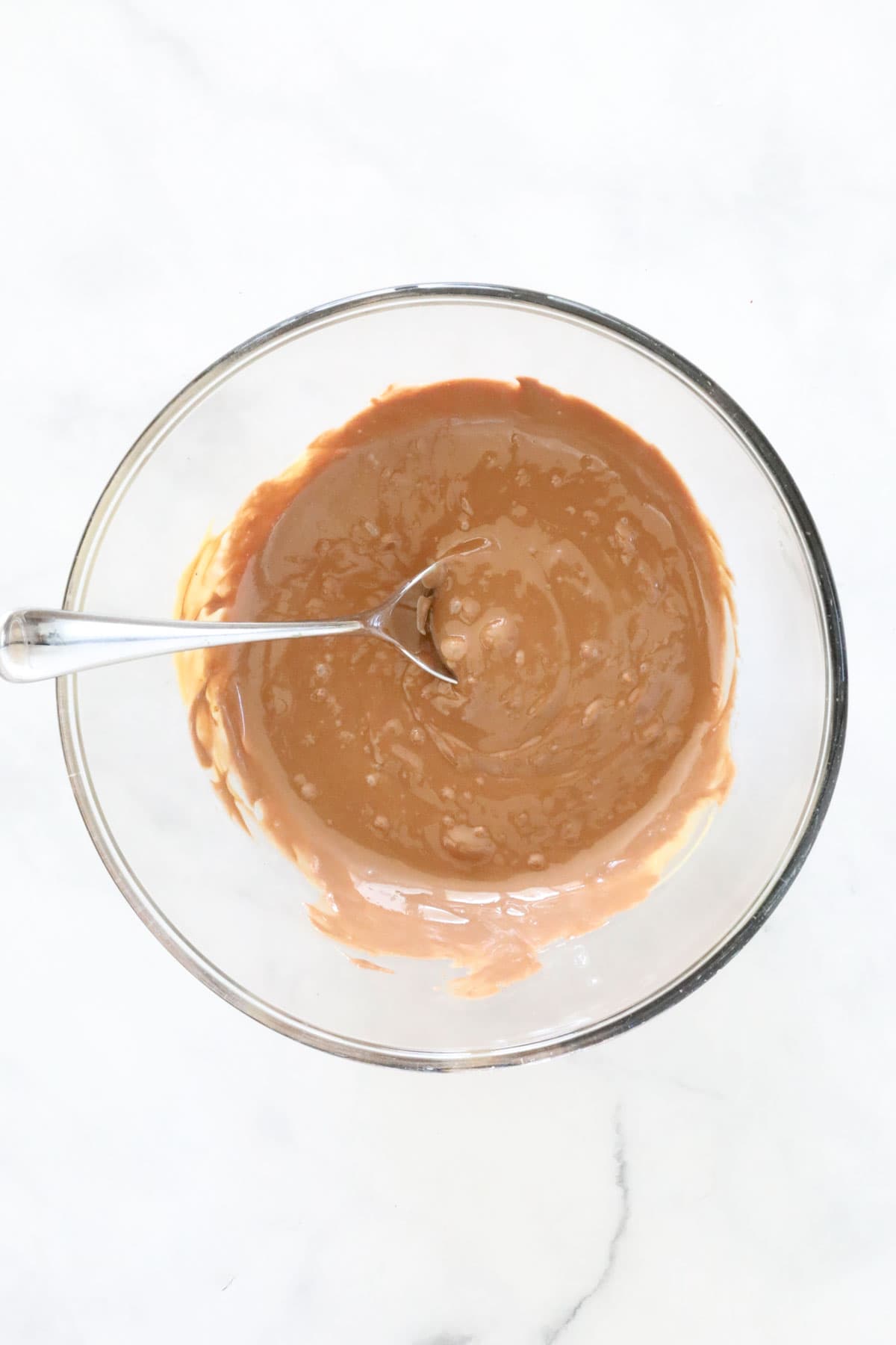 Milk chocolate and peanut butter melted together in a glass bowl.