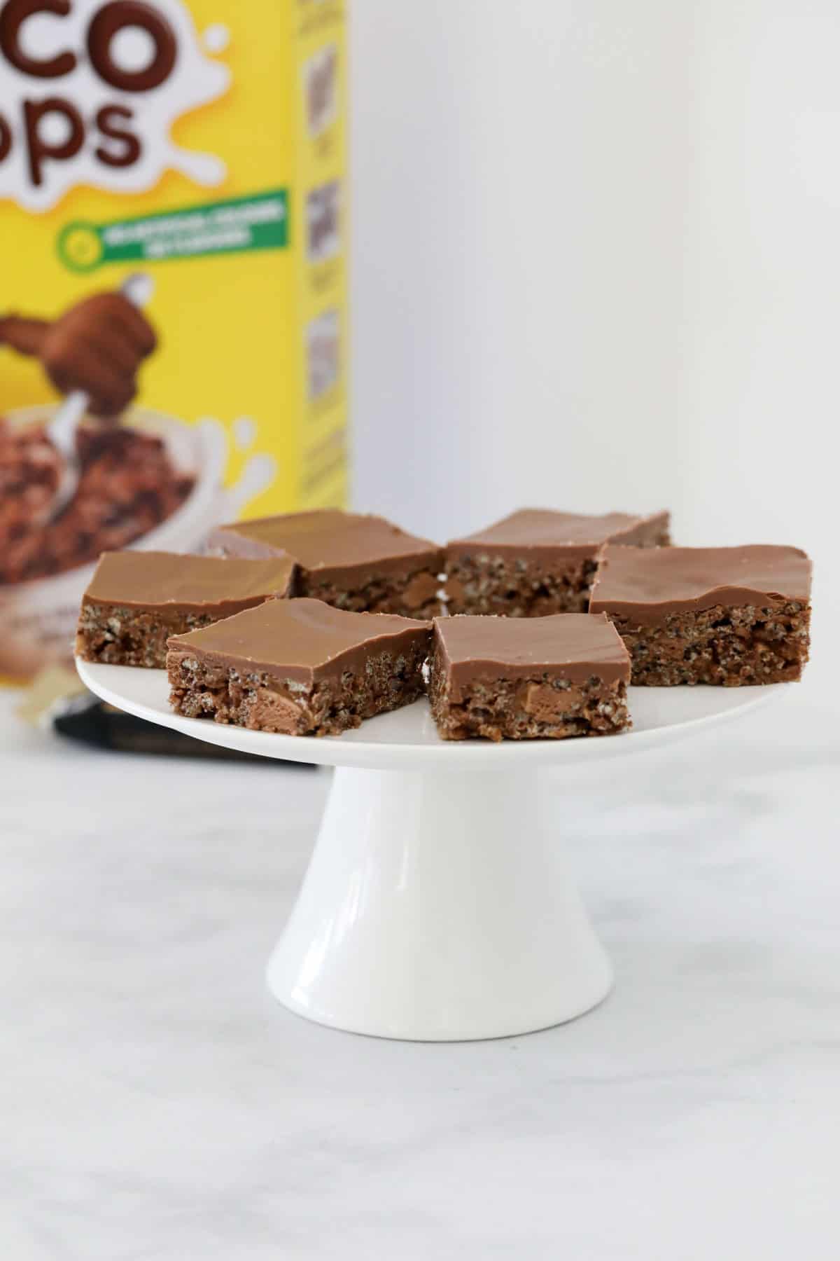 A white cake stand with pieces of Mars Bar slice on it.