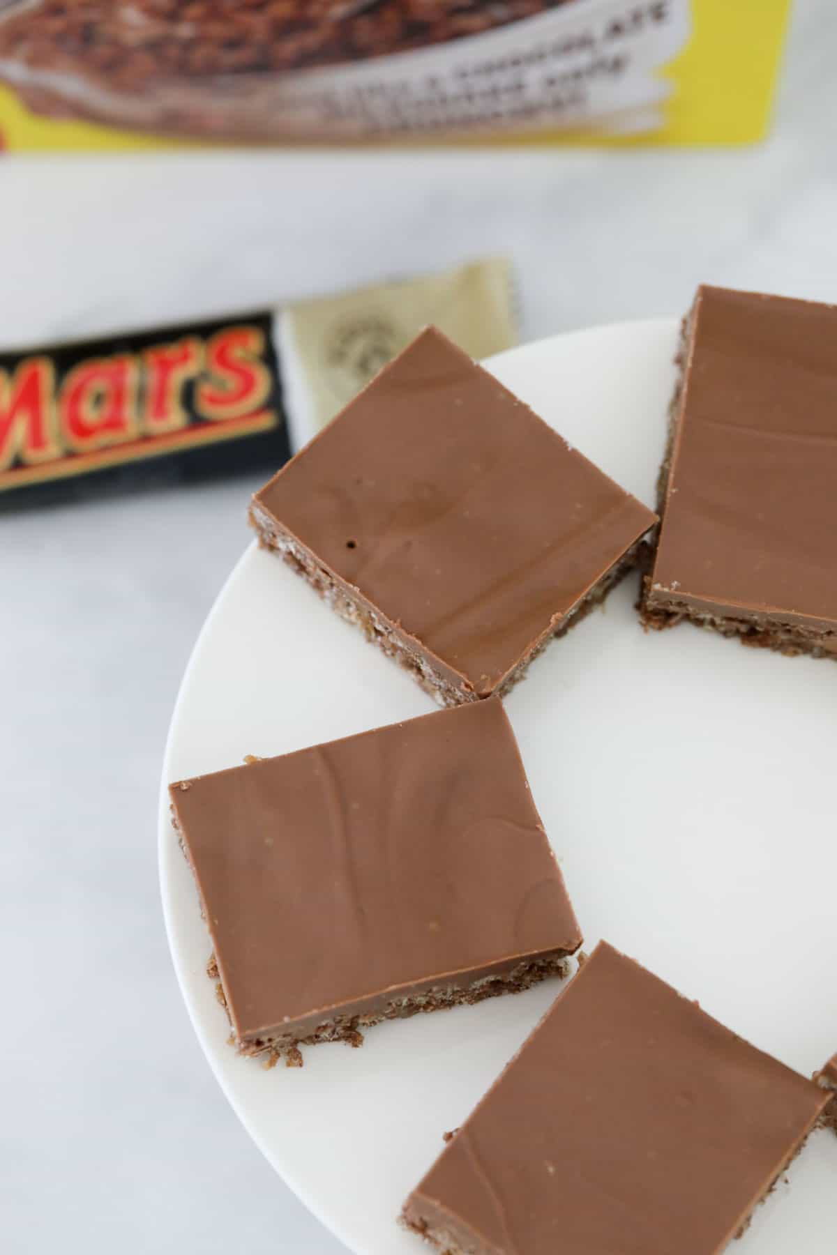 An overhead shot of squares of Coco Pop Mars Bar slice on a white plate.