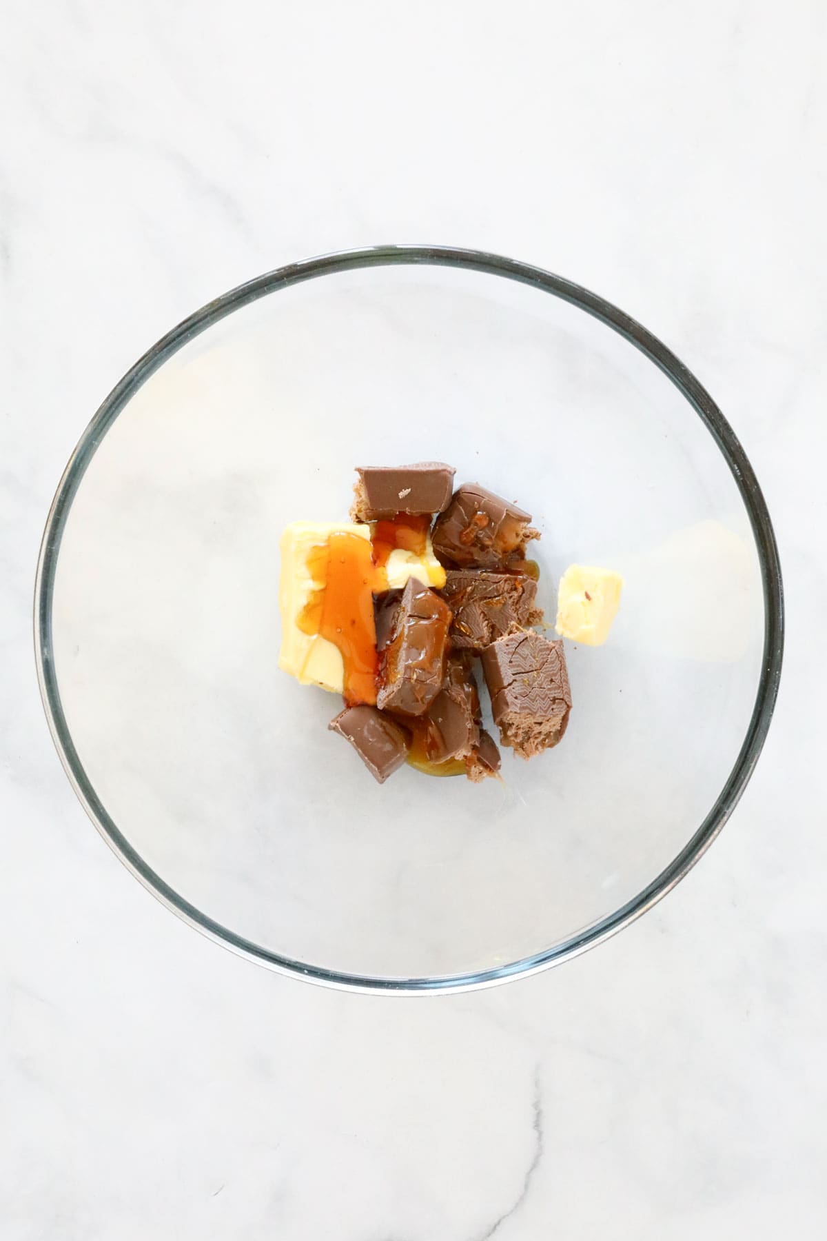 Butter, golden syrup and chopped Mars Bars in a clear glass bowl.