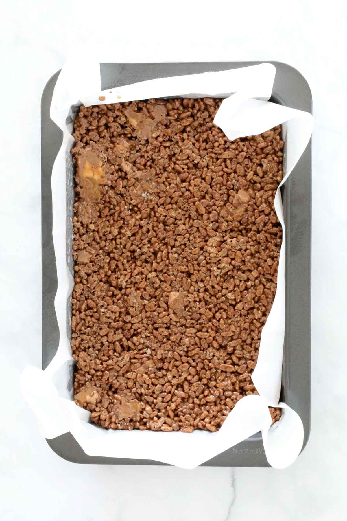 The crispy chocolate mixture pressed firmly into the lined baking tin.