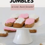 Pink and white iced honey jumbles on a white cake stand.