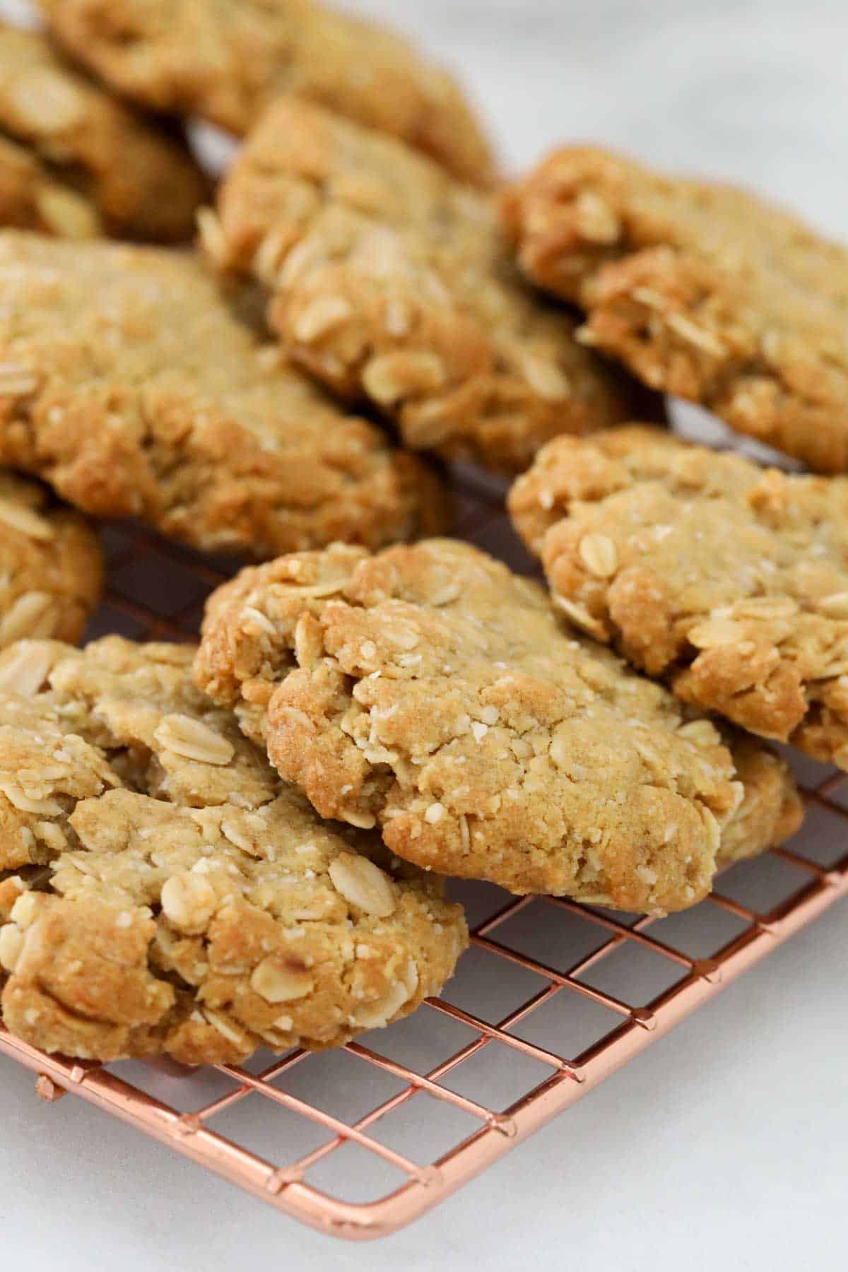 A batch of ANZAC biscuits cooling on a wire tray.