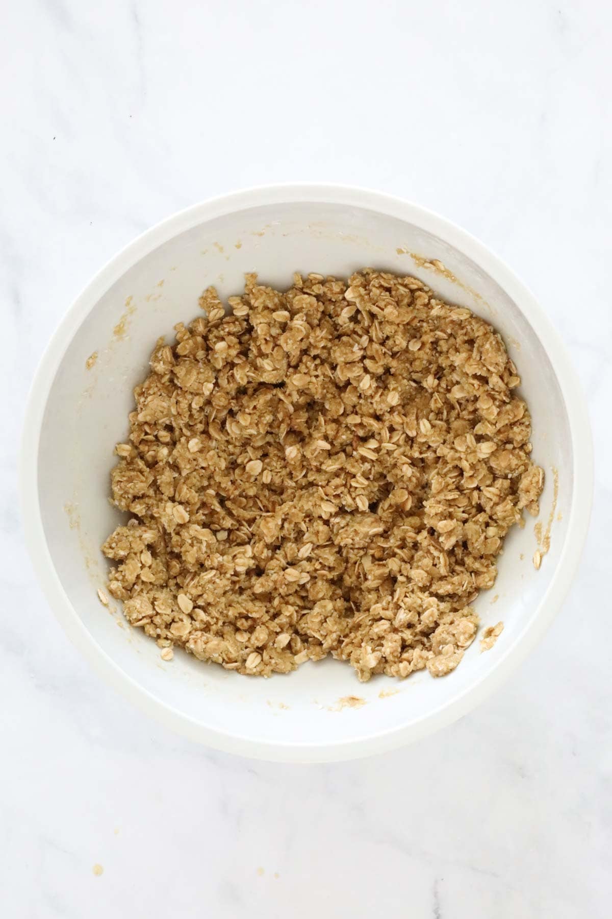 ANZAC biscuit mixture in a large white bowl.