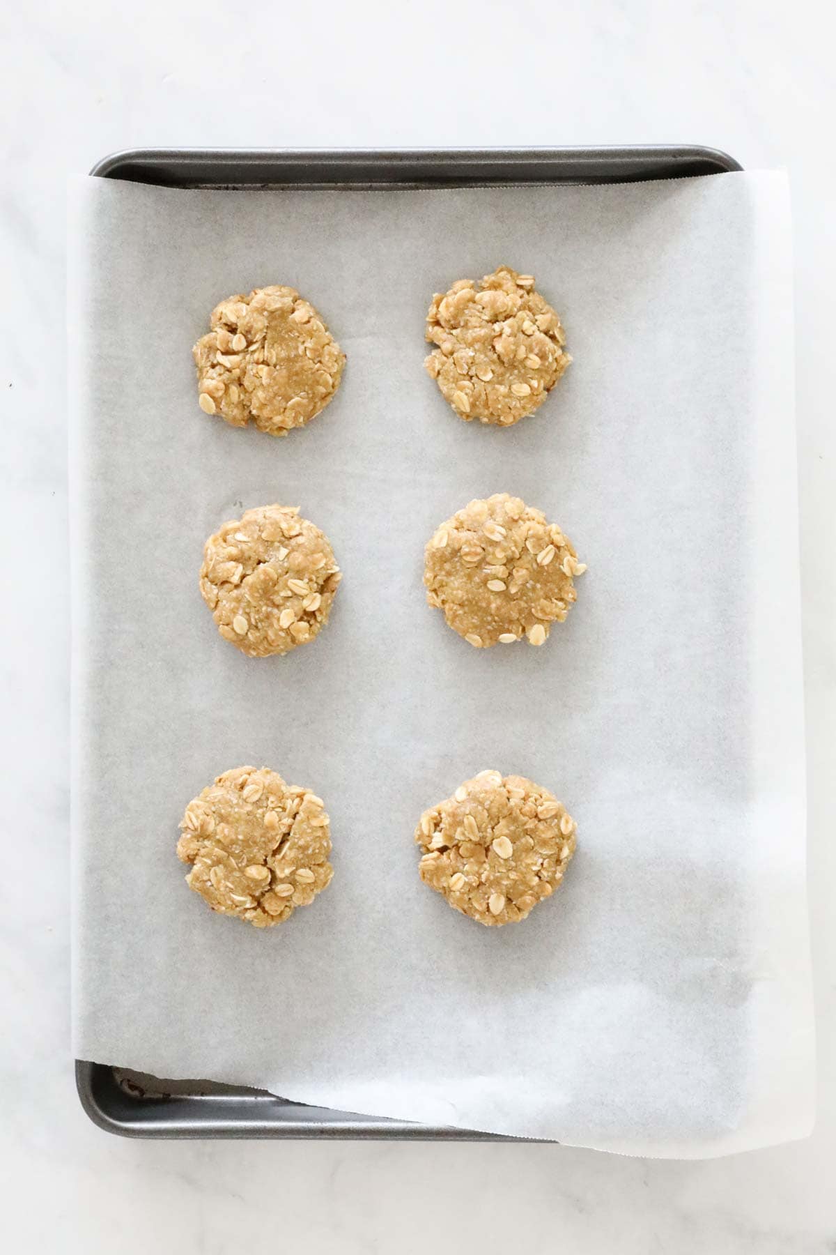 Balls of biscuit mixture placed on paper lined baking trays.