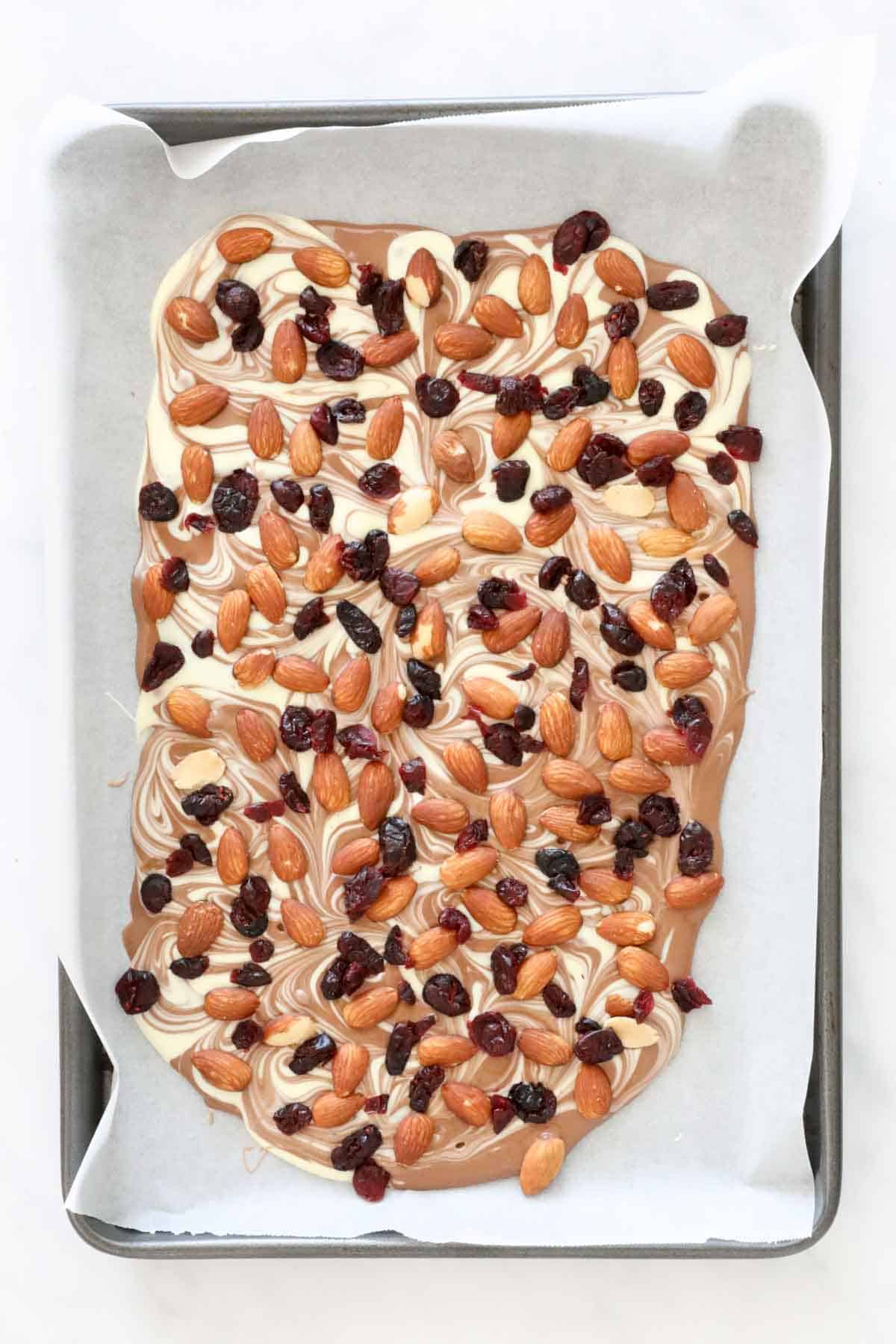 Roasted almond and cranberries spread over melted milk chocolate and white chocolate.