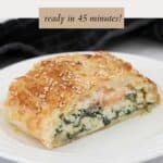 A slice of pie on a plate, showing its creamy salmon, ricotta and spinach filling.