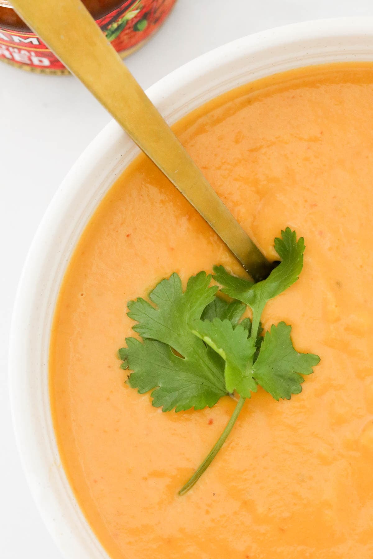 overhead shot of pumpkin soup with a gold spoon.