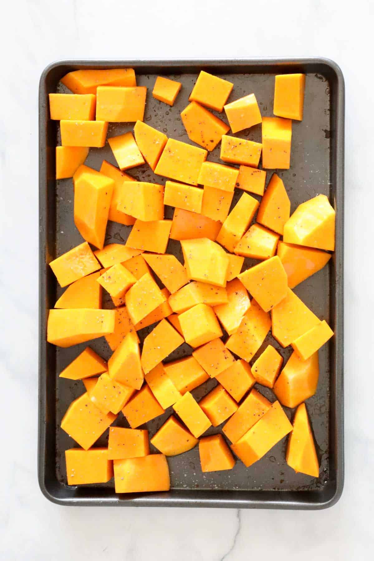 Diced pumpkin pieces on a baking tray.