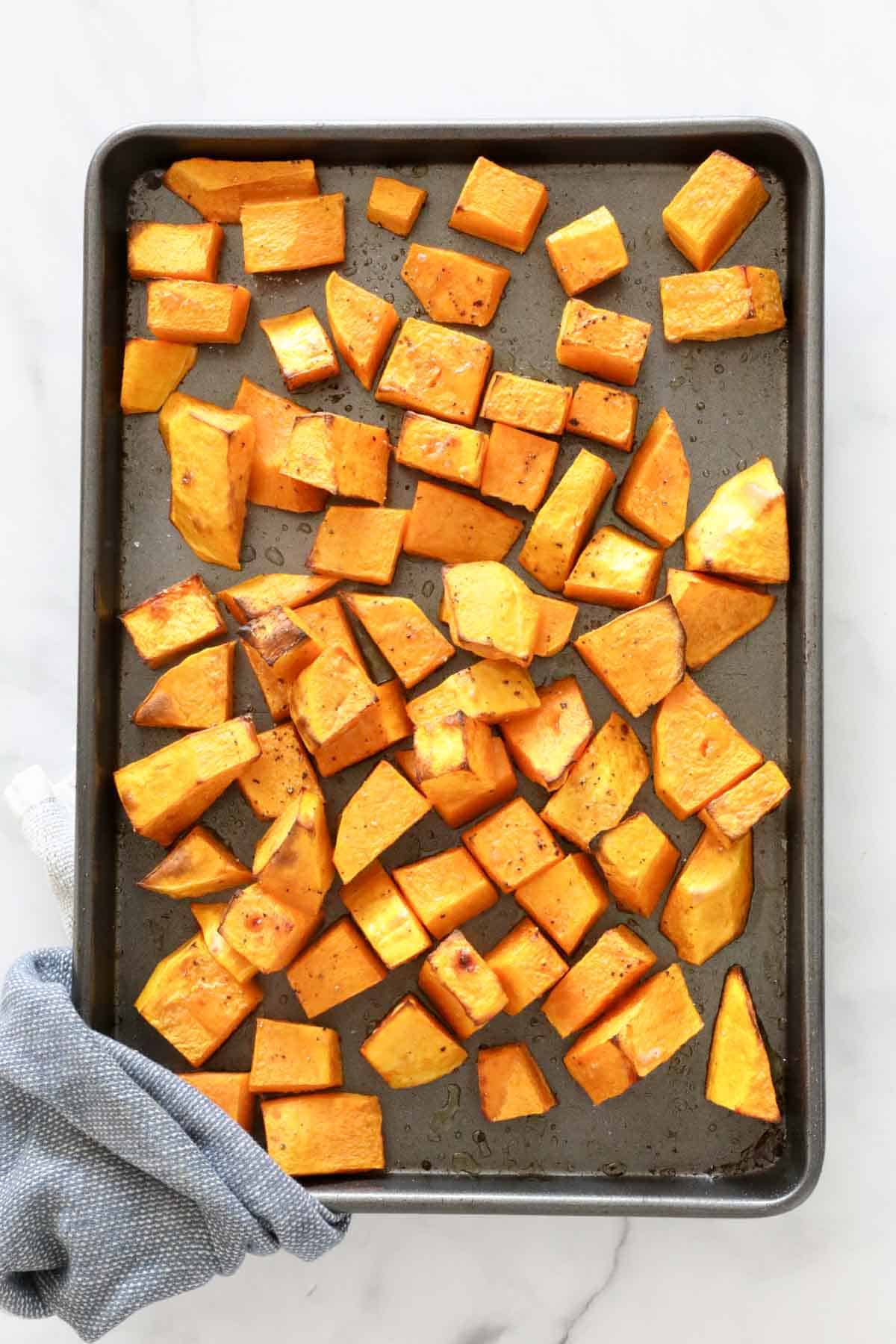 Chunks of roast pumpkin on a baking tray.