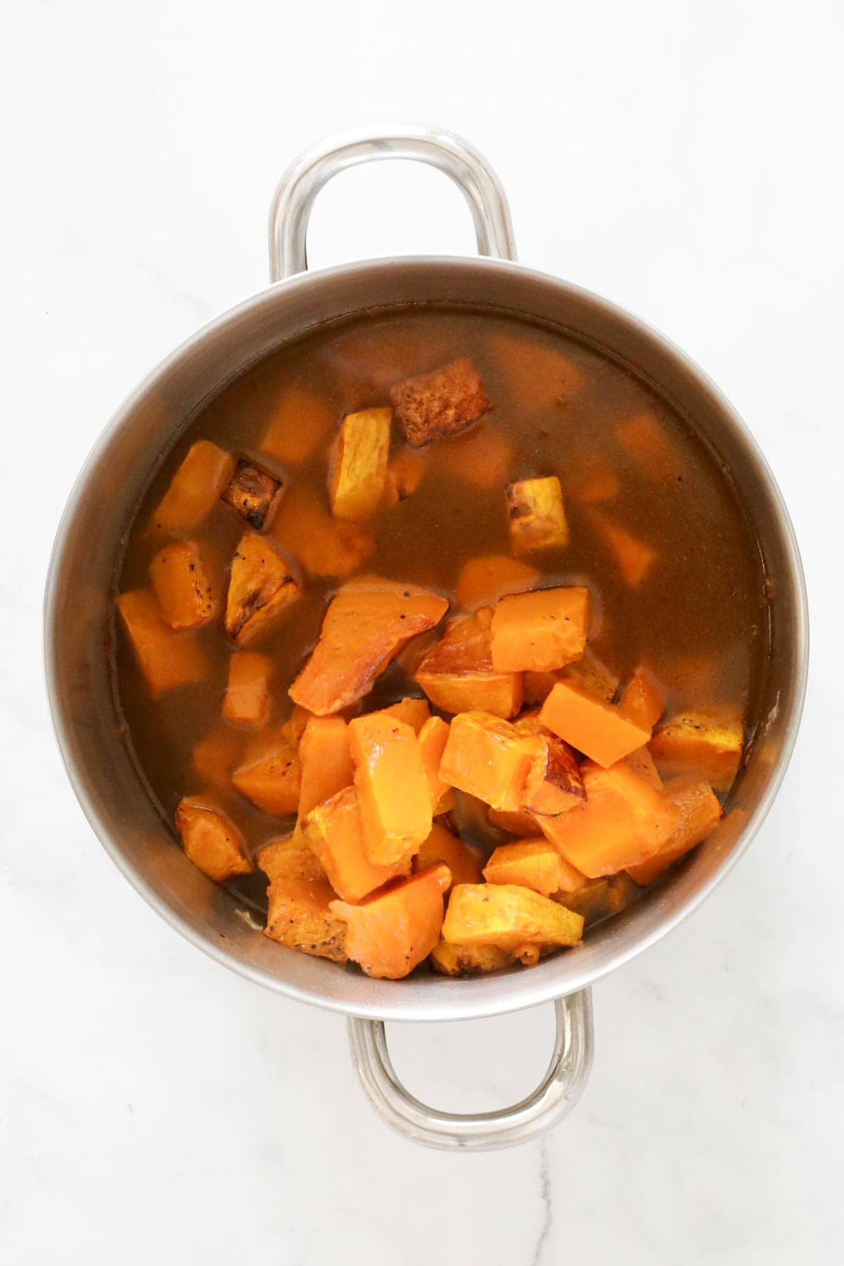 Roasted pumpkin chunks and stock added to saucepan.