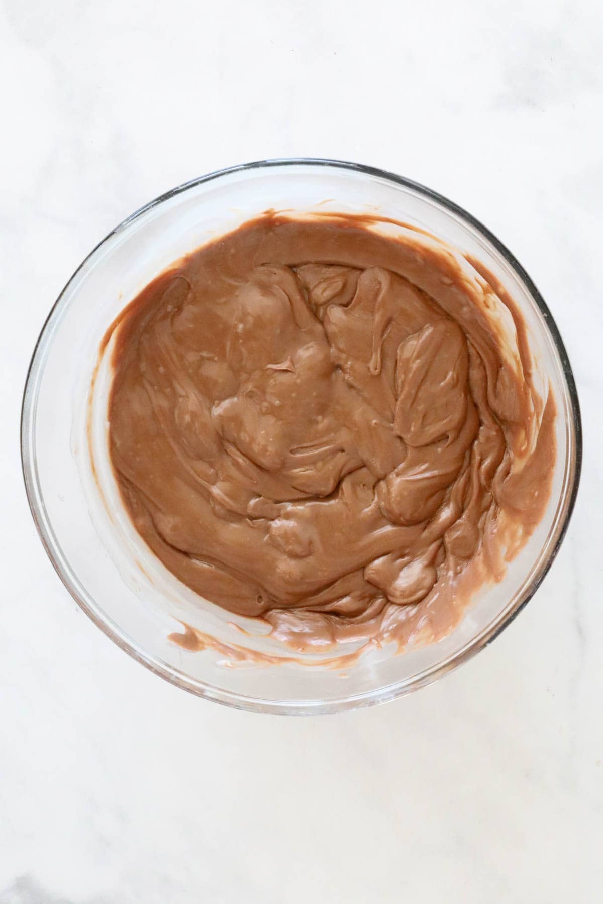 Melted chocolate and condensed milk mixed in a large clear bowl.