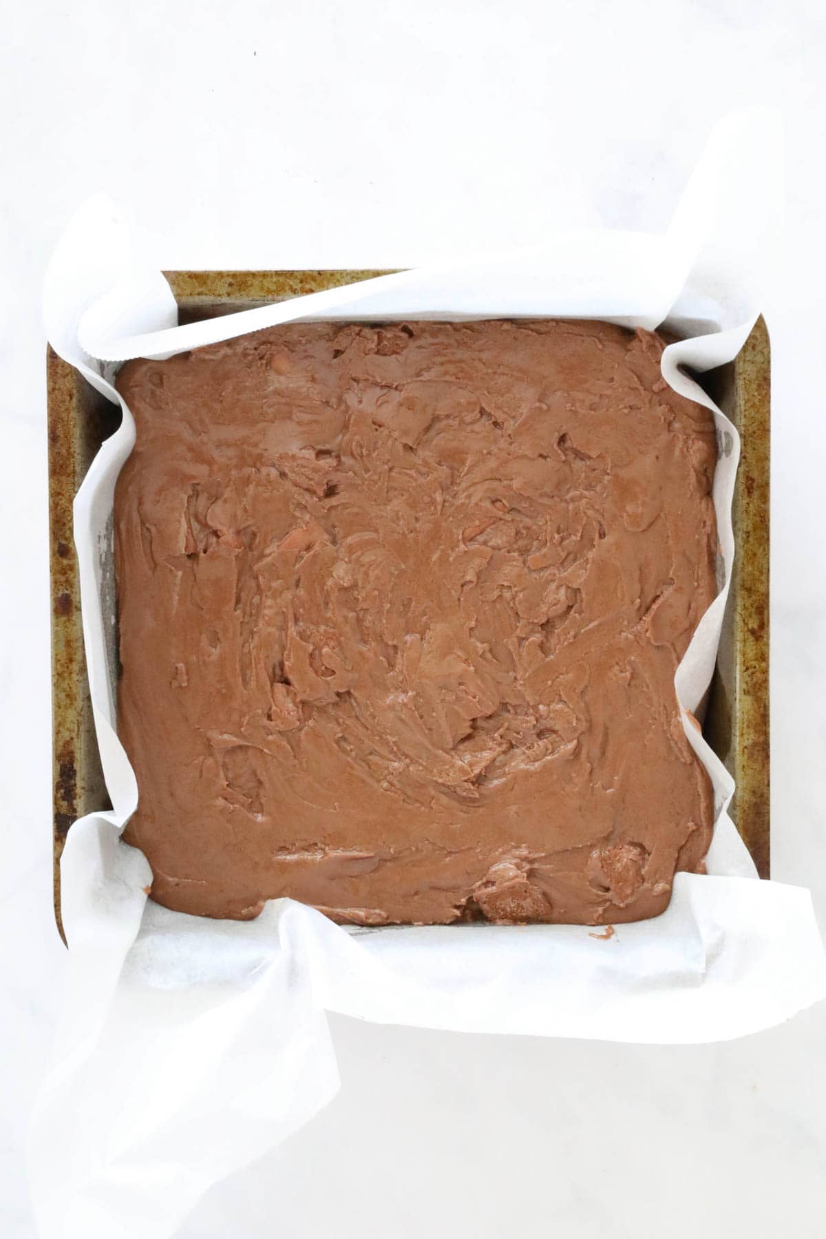 Tim Tam Fudge spread into a lined baking tin.