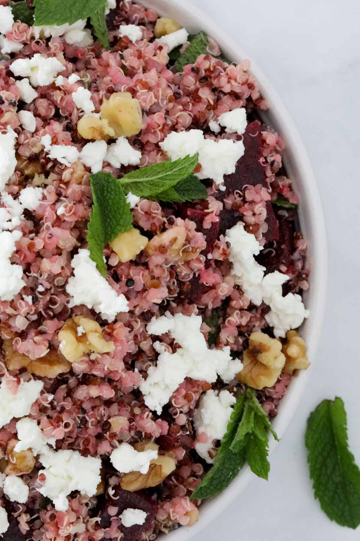 A salad of walnuts, quinoa and beetroot with crumbled feta and chopped mint leaves over the top.