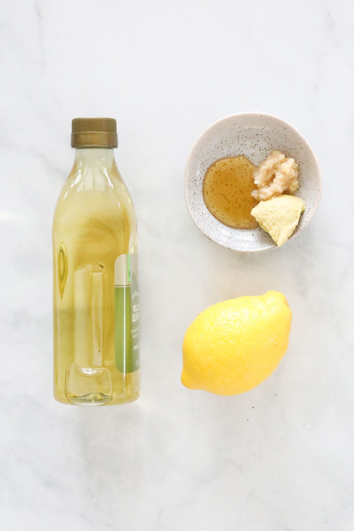 Ingredients for a lemon vinaigrette placed on a bench.