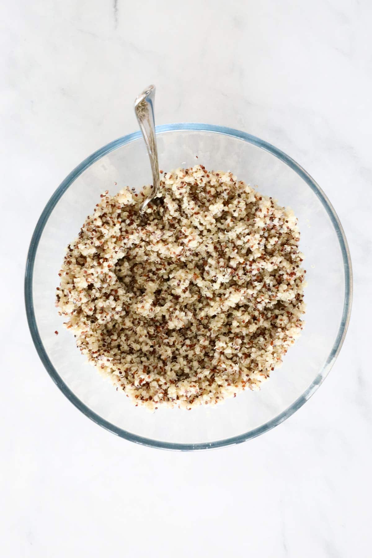 Quinoa cooked and fluffed up, in a clear glass bowl.