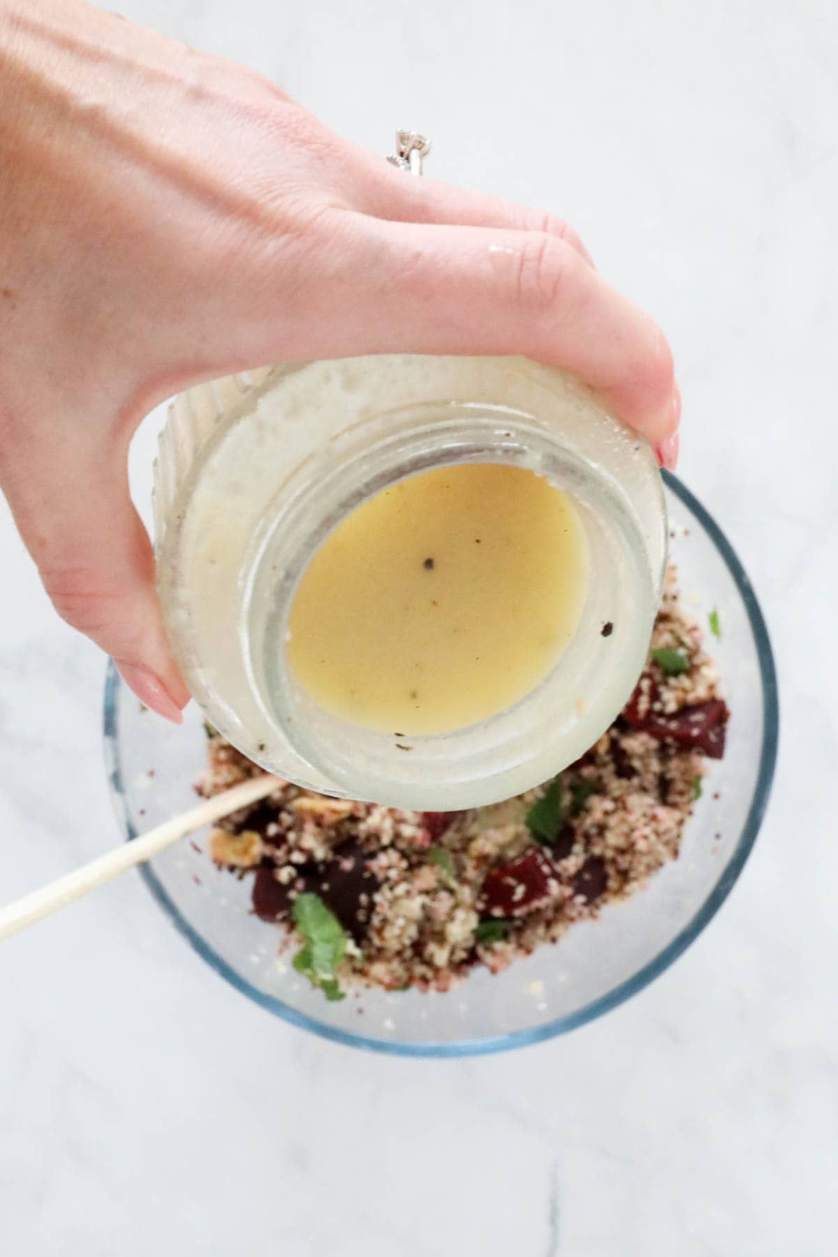 The lemon vinaigrette being poured over the salad.