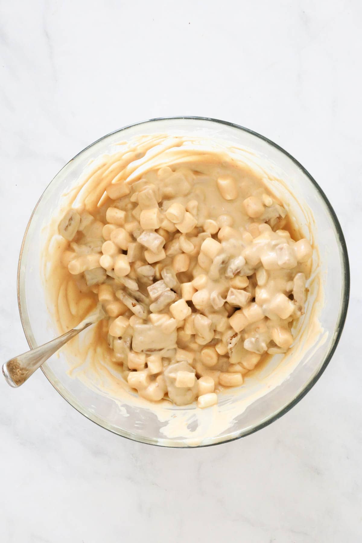 All ingredients coated in white chocolate mixture, in a bowl.