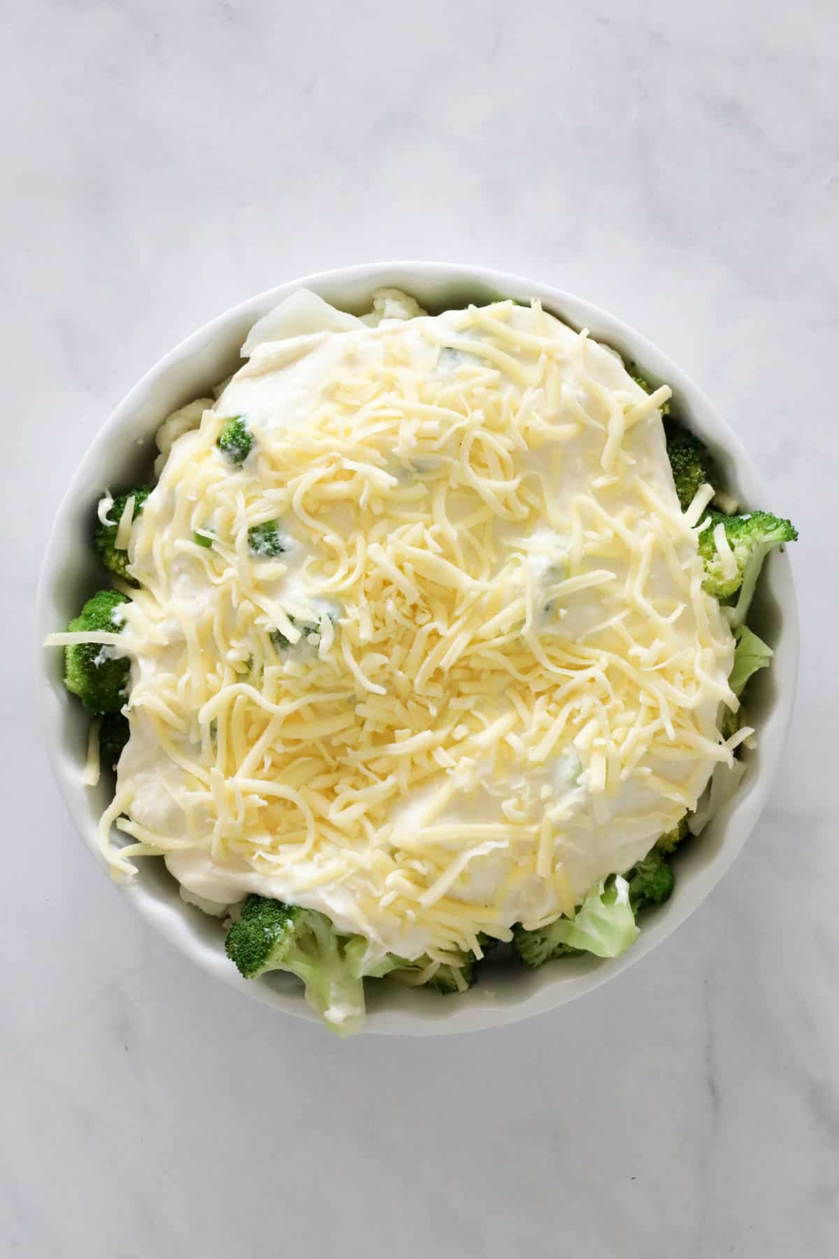 Cheese sauce poured over vegetables, and extra cheese sprinkled on top.
