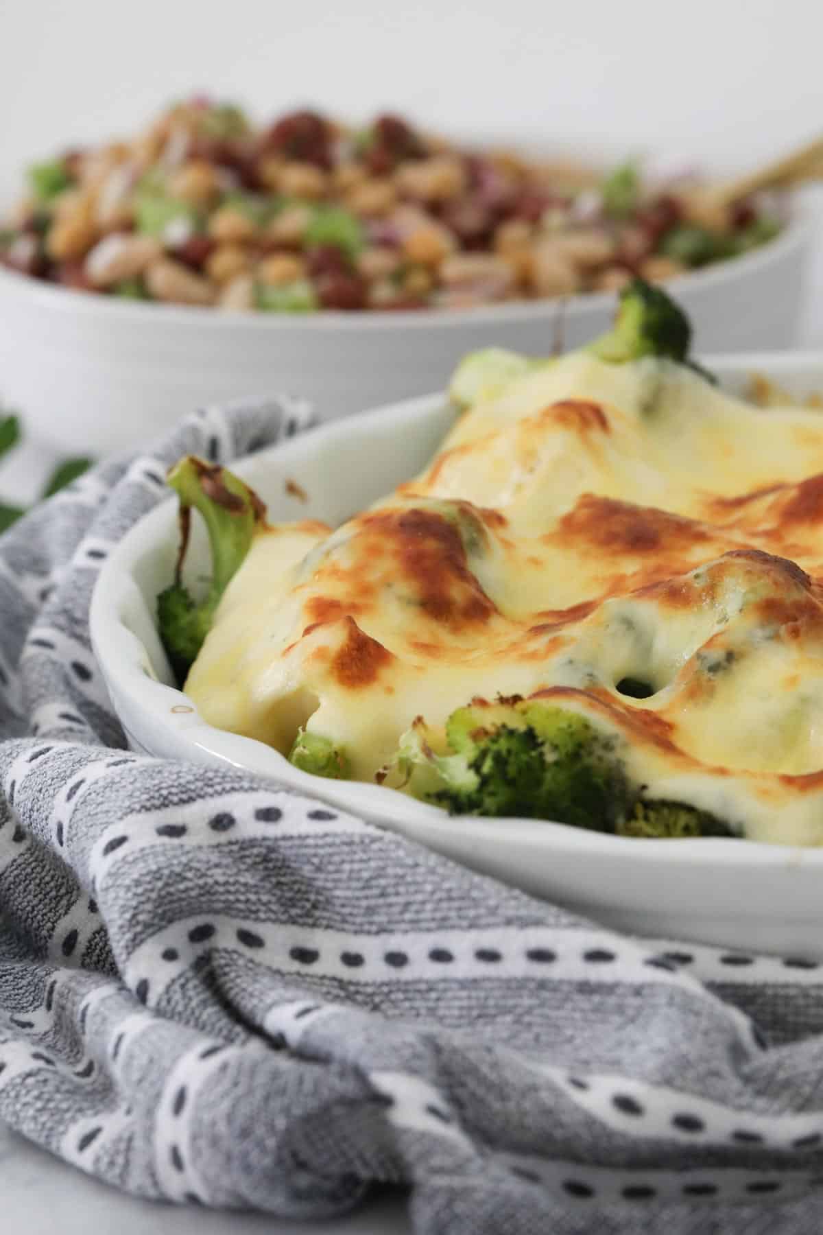 A plate of veggie bake in front of the rest in a white baking dish.
