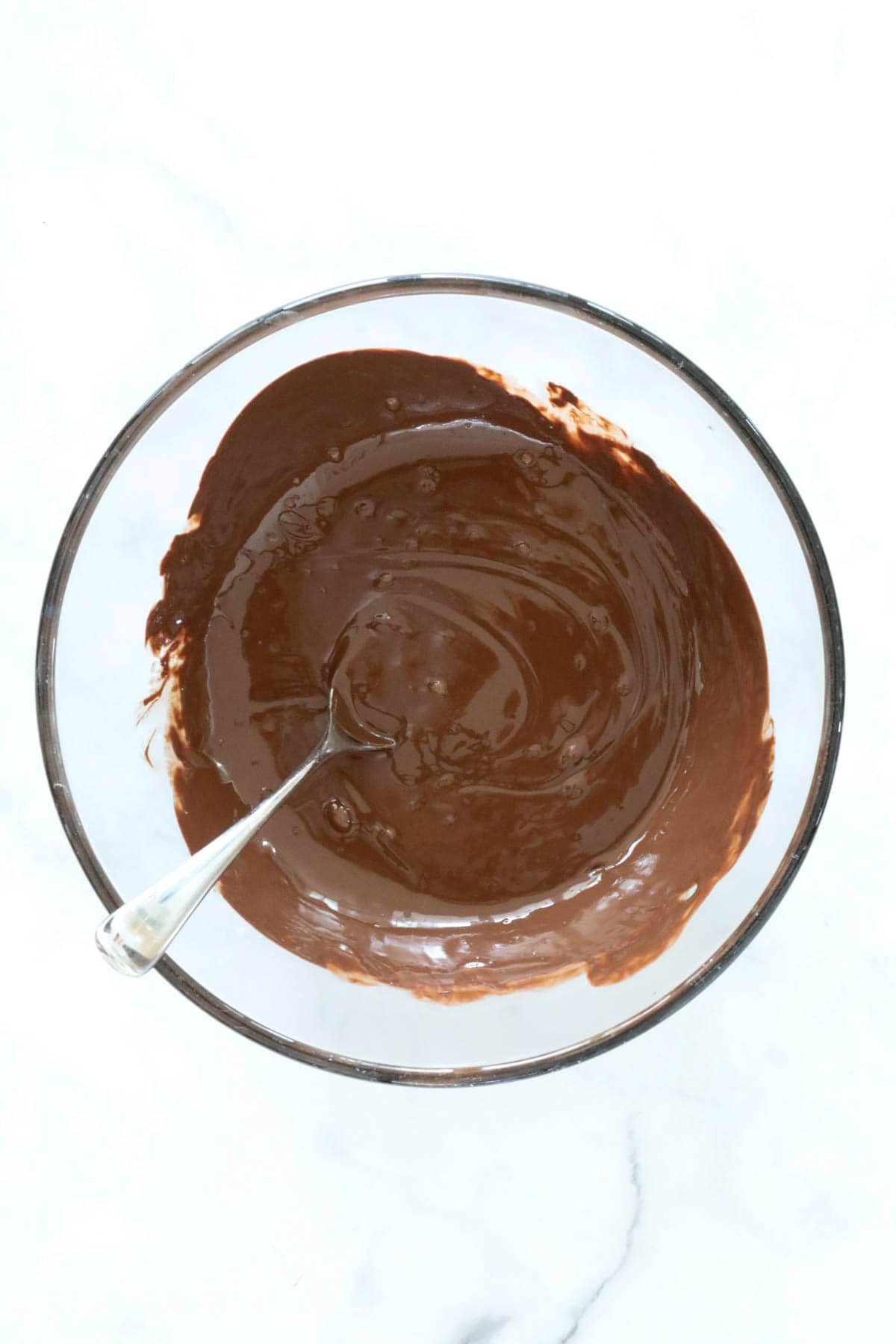 Melted chocolate in a clear glass bowl.