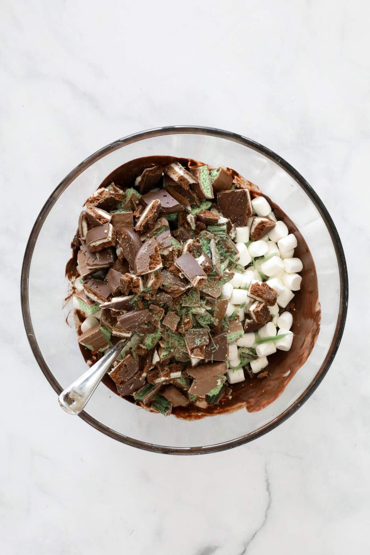 Chopped ingredients added to melted chocolate in a large bowl.