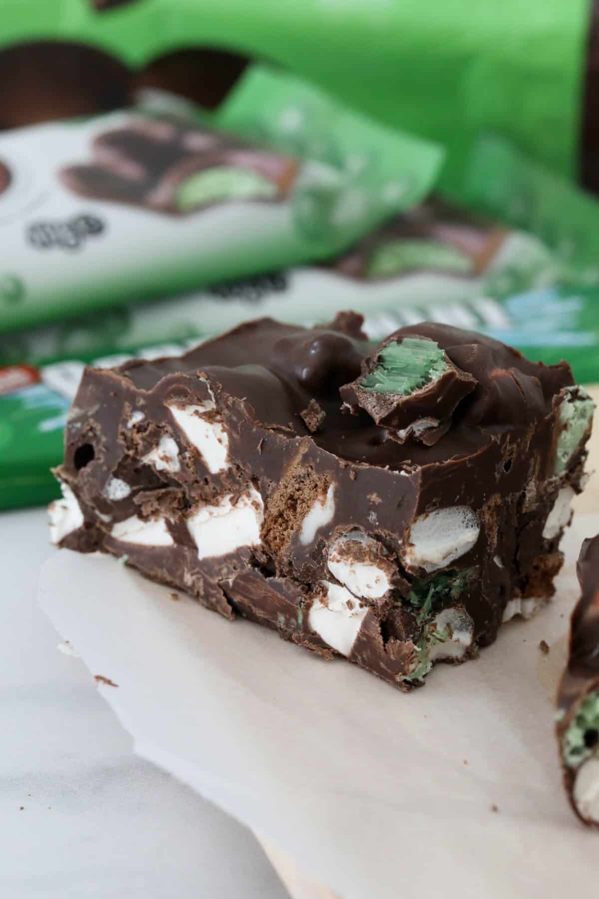 A close up of a square of mint rocky road with mint chocolate bars in the background.