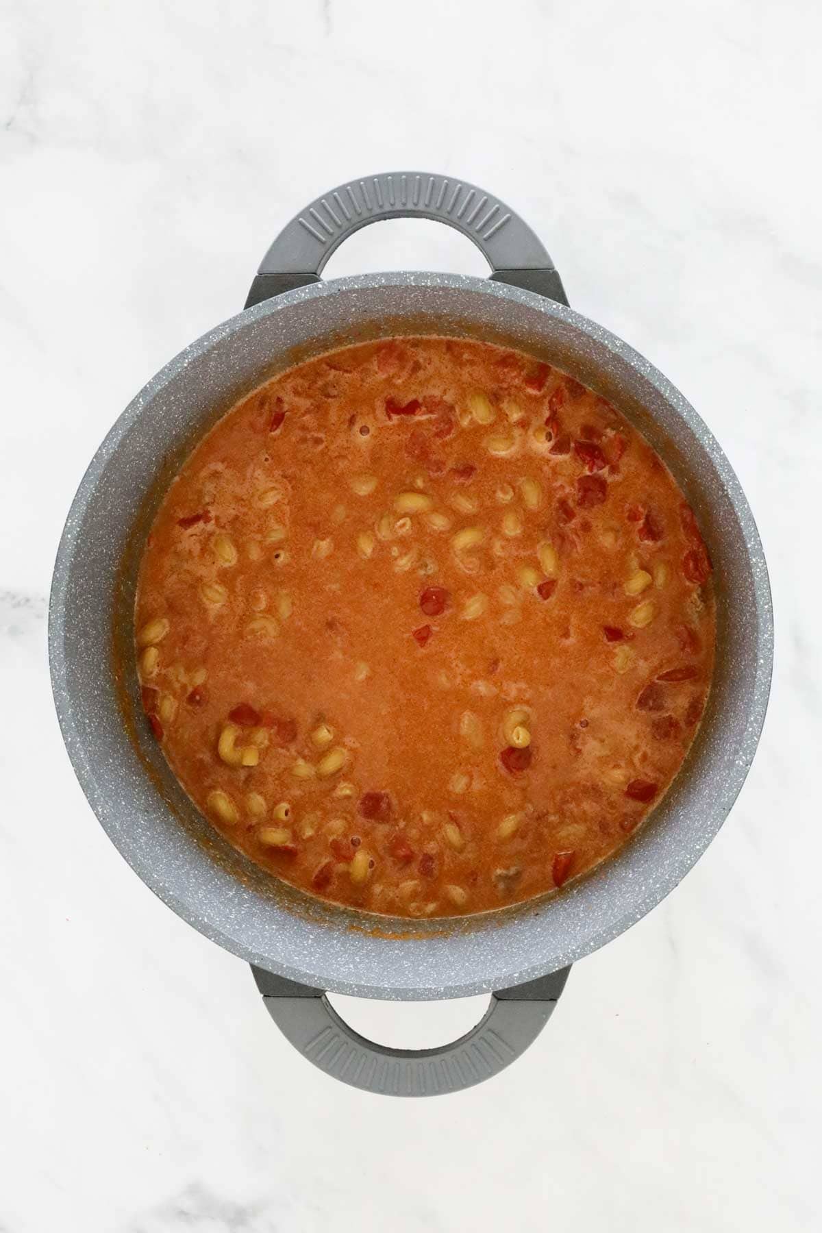 Pasta cooking in the pan with meat, stock and seasonings.